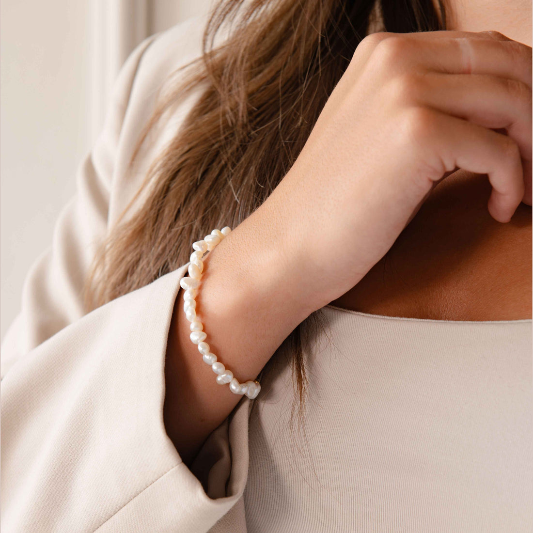 Wit zoetwater parel armband met goud kleurig edelstaal en verlengketting op model met wit jasje | Adalyn