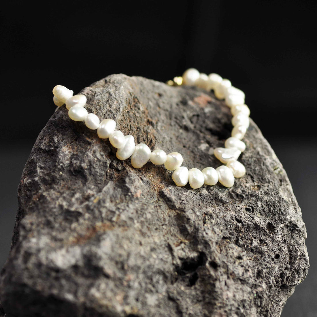 Wit zoetwater parel armband met goud edelstalen slotje en verlengketting liggend op rots | Adalyn