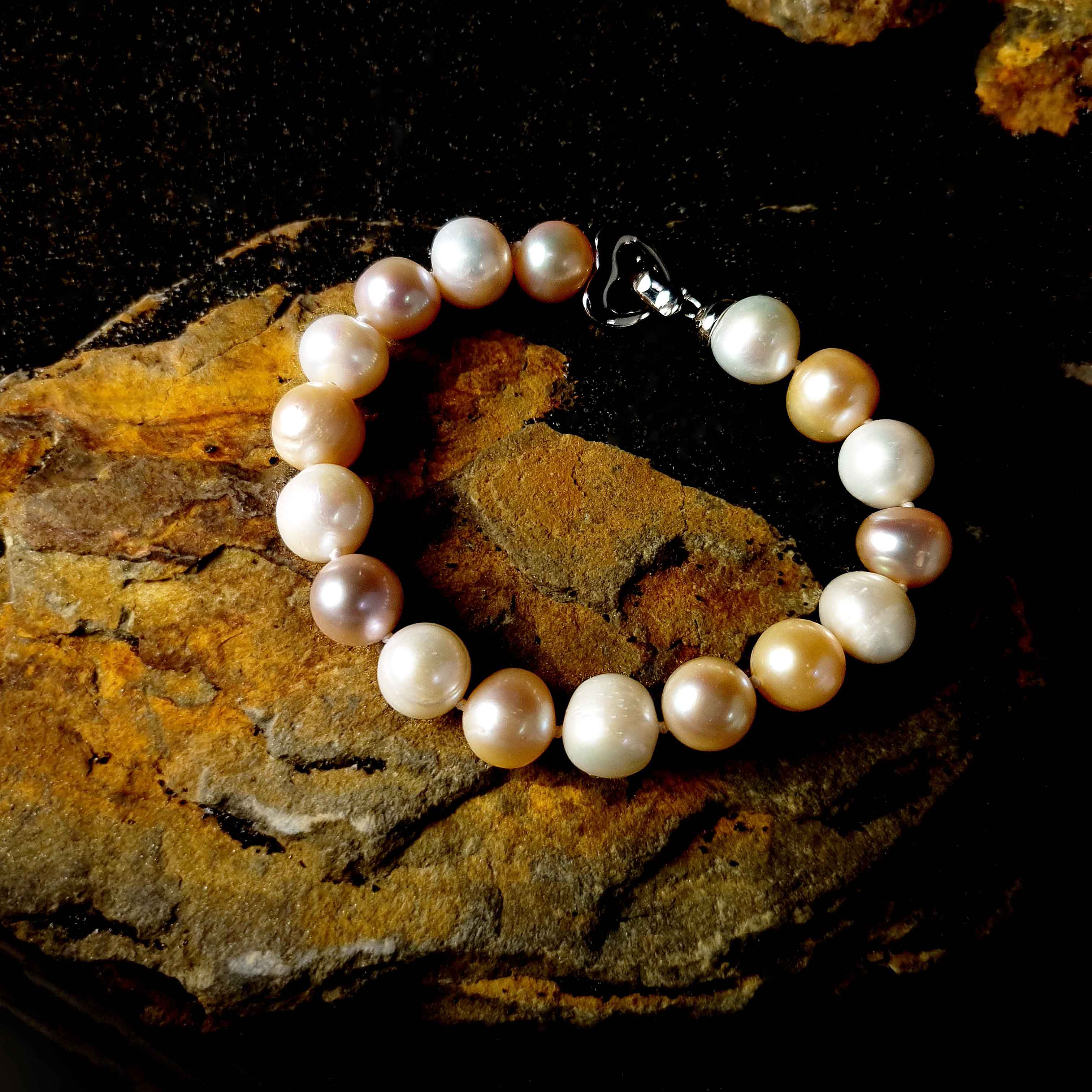 Zoetwater parel armband met witte, zalm en roze parels liggend op steen | Big Bold Soft Colors