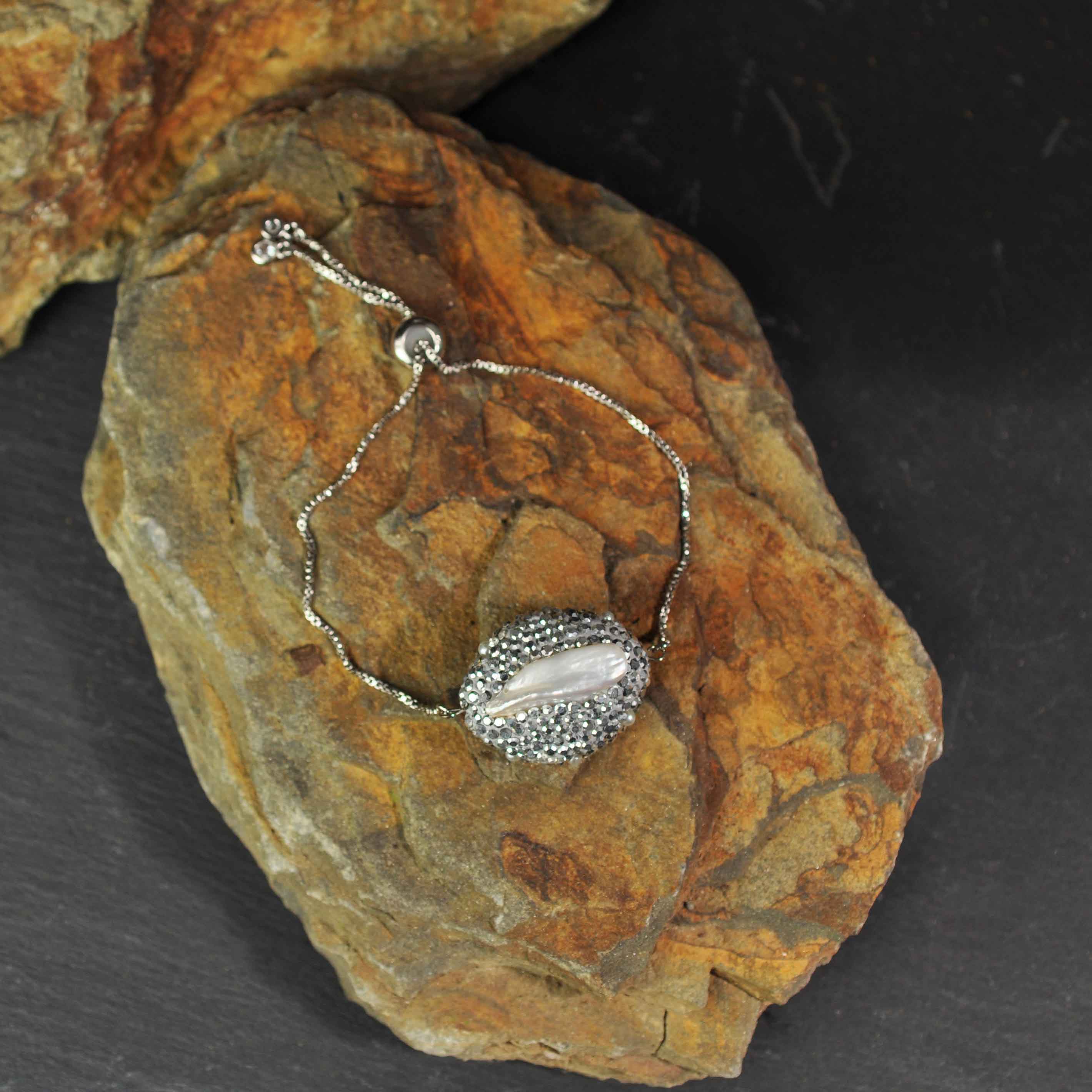 Wit zoetwater parel armband met stras steentjes, glitter armband met parel en schuifsluiting liggend op steen | Bright Biwa Silver