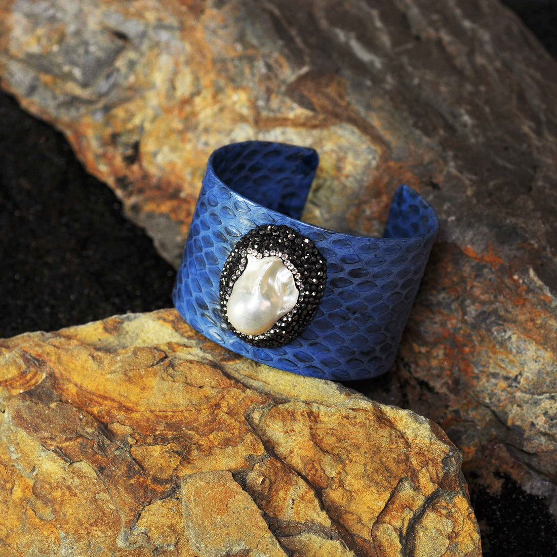 Zoetwater parel armband met witte parel, stras steentjes en blauw leer liggend op steen | Bright One Big Pearl Blue Leather