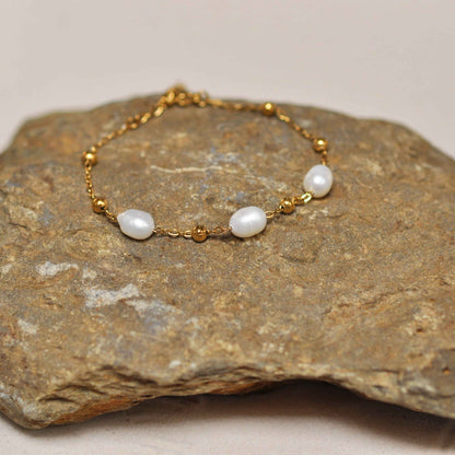 Wit zoetwater parel armband met goud edelstaal liggend op steen | Parel armband Eline Goud
