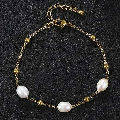 Wit zoetwater parel armband met goud edelstaal liggend op zwart zand | Parel armband Eline Goud