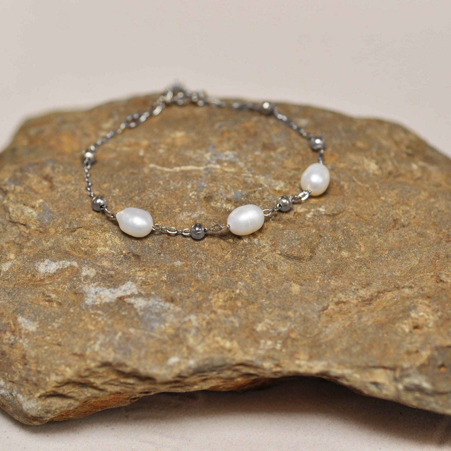 Wit zoetwater parel armband met zilver edelstaal liggend op steen | Parel armband Eline Zilver