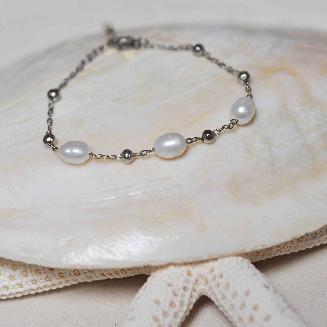 Wit zoetwater parel armband met zilver edelstaal liggend op schelp | Parel armband Eline Zilver