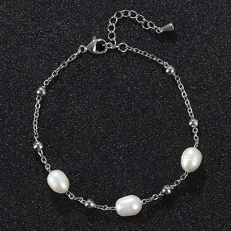 Wit zoetwater parel armband met zilver edelstaal liggend op zwart zand | Parel armband Eline Zilver