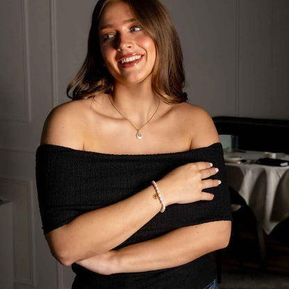 Wit zoetwater parel armband met symbool van sterrenbeeld schorpioen in edelstaal op model met jurk | Gouden Sterrenbeeld Schorpioen