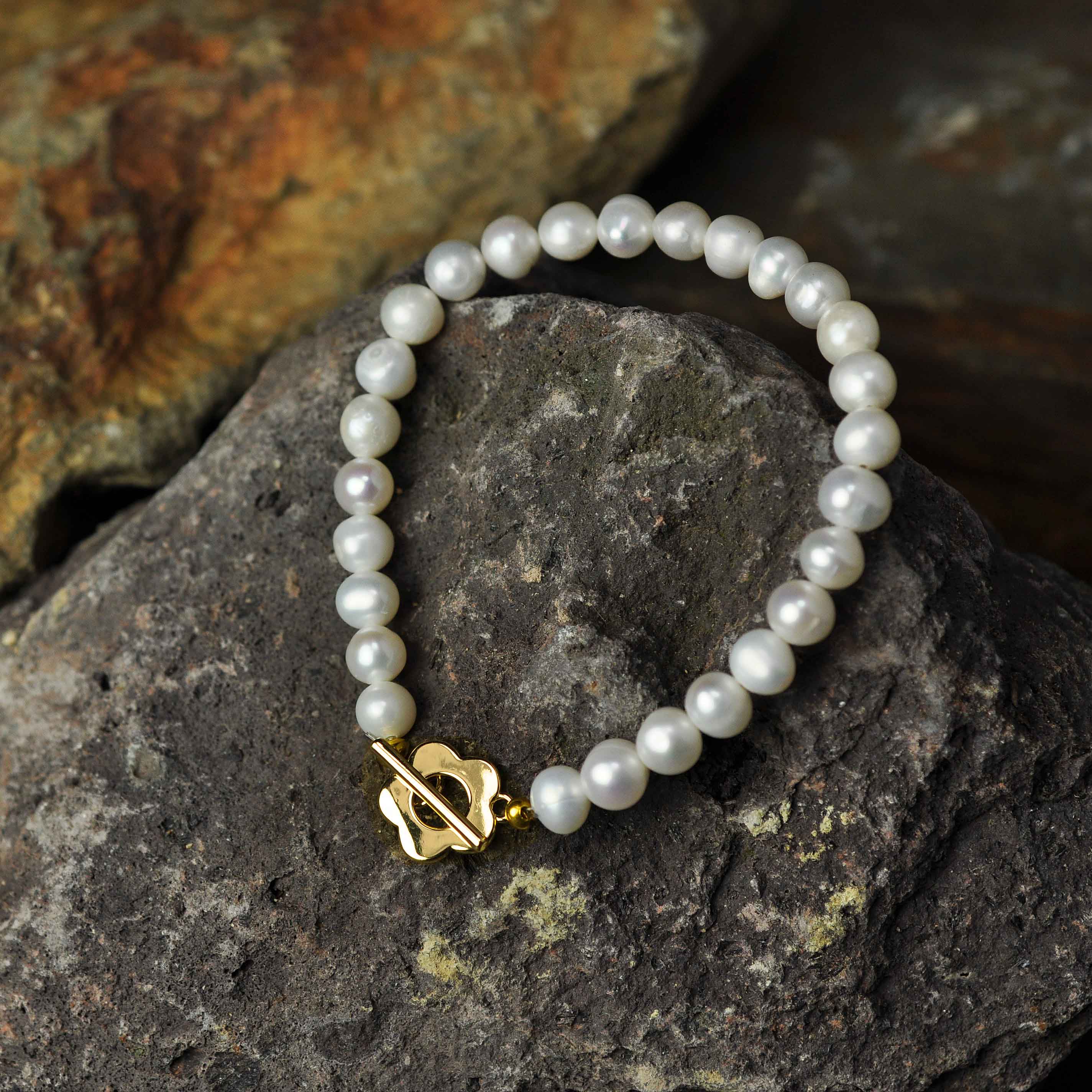 Wit zoetwater parel armband met gouden bloem slotje liggend op steen | Pearl Golden Flower