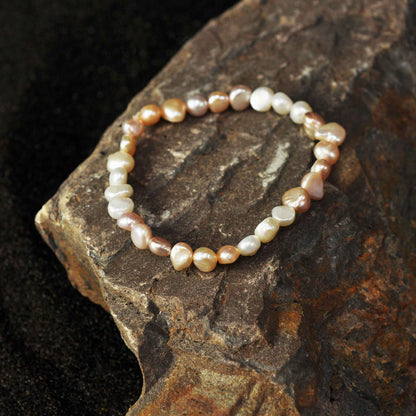 Zoetwater parel armband met witte, zalm en roze parels liggend op steen, bovenaanzicht | Pearl Trio Soft Colors