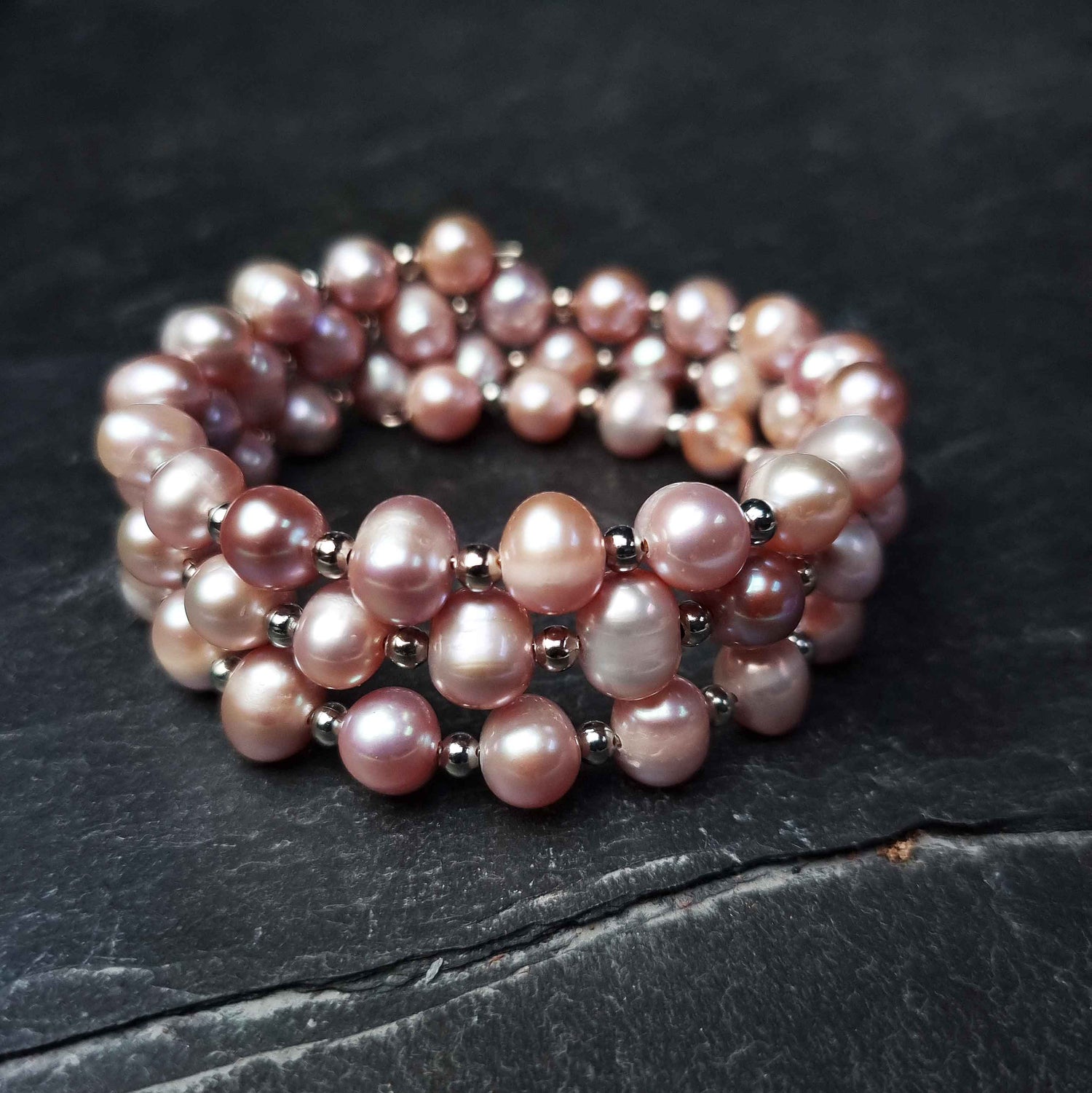 Roze zoetwater parel wikkelarmband liggend op leisteen| Pink Pearl Wrap