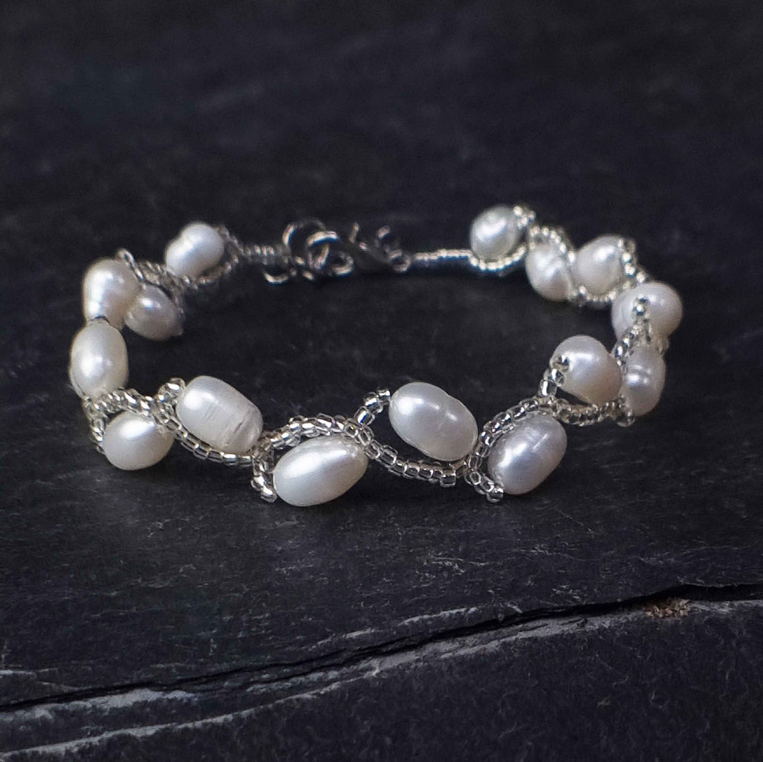Zoetwater parel armband met witte parels liggend op leisteen| Twist Pearl White