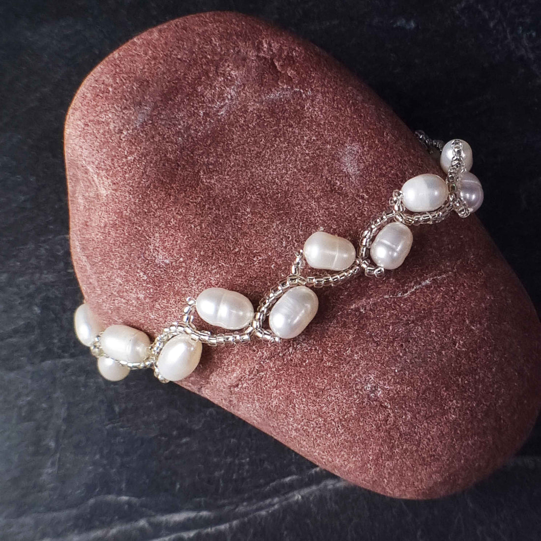 Zoetwater parel armband met witte parels liggend op rode steen | Twist Pearl White