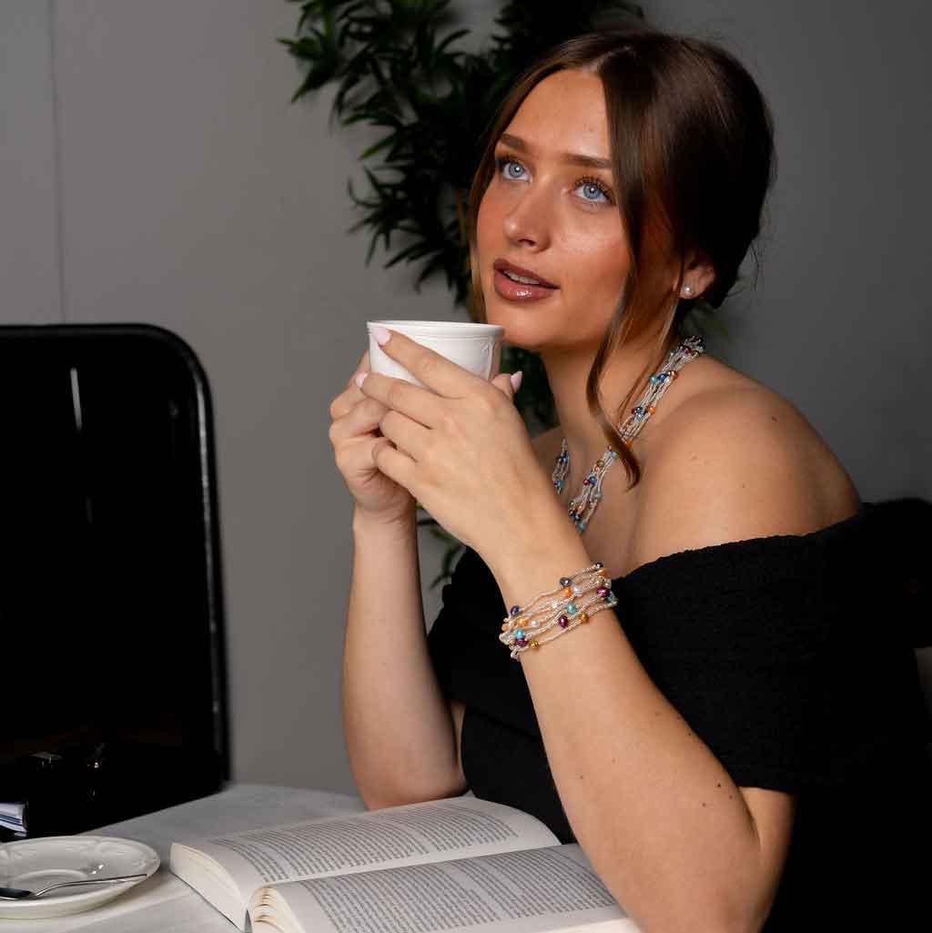 Zoetwater parel armband met 7 strengen bontgekleurde parels en zilveren glaskraaltjes met magneetslot met model aan tafel | set Viva