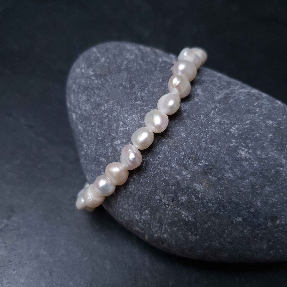Wit zoetwater parel armband liggend op kei | Weaca