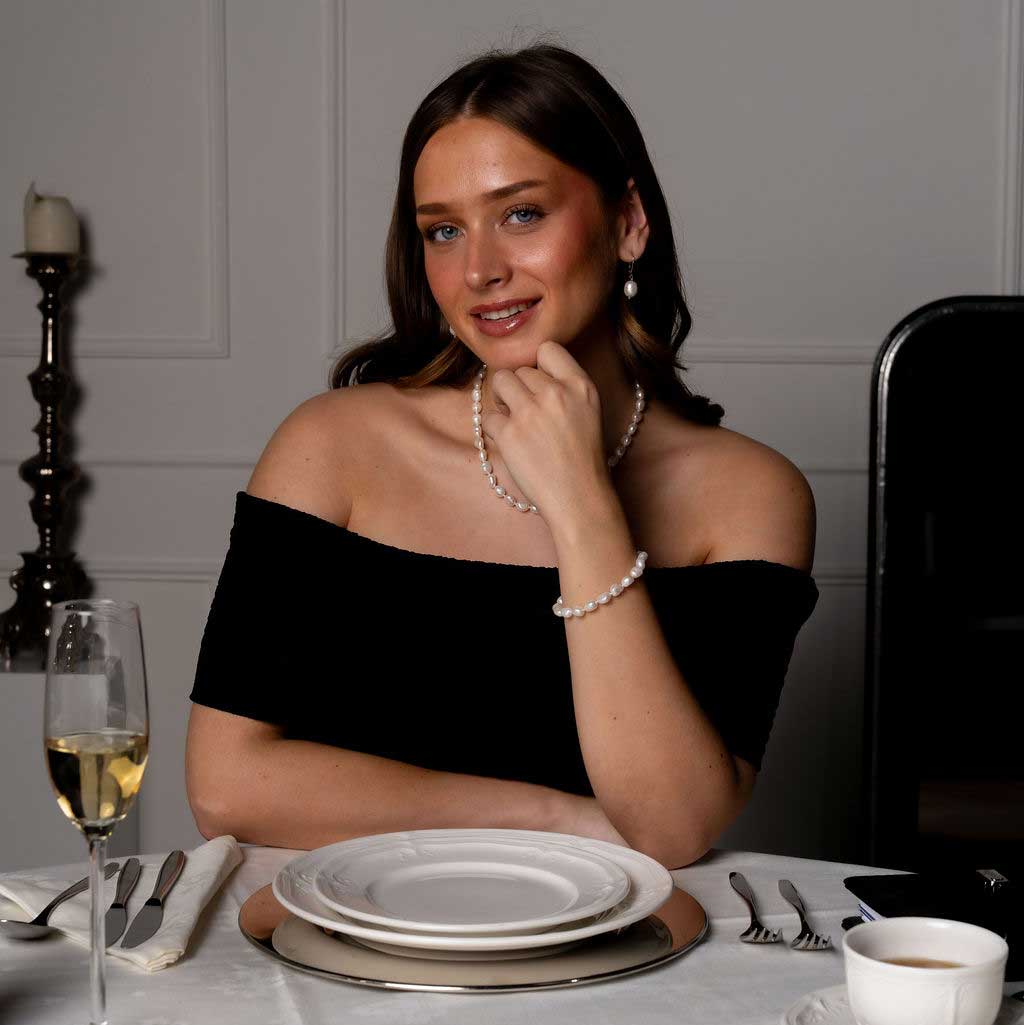 Wit zoetwater parel armband, handgeknoopt op model aan tafel | Wola