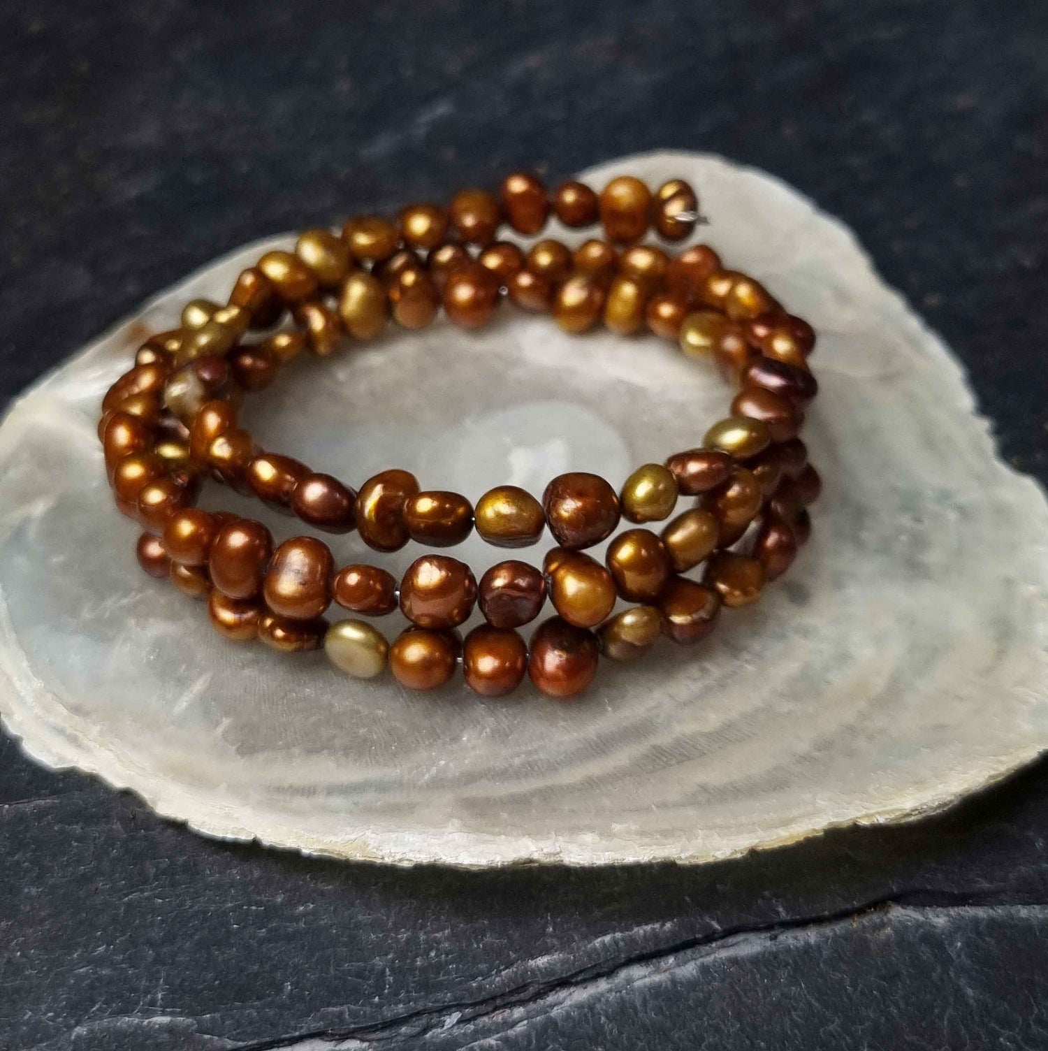 Zoetwater parel wikkel armband met bruin parels liggend op witte schelp | Zen Brown