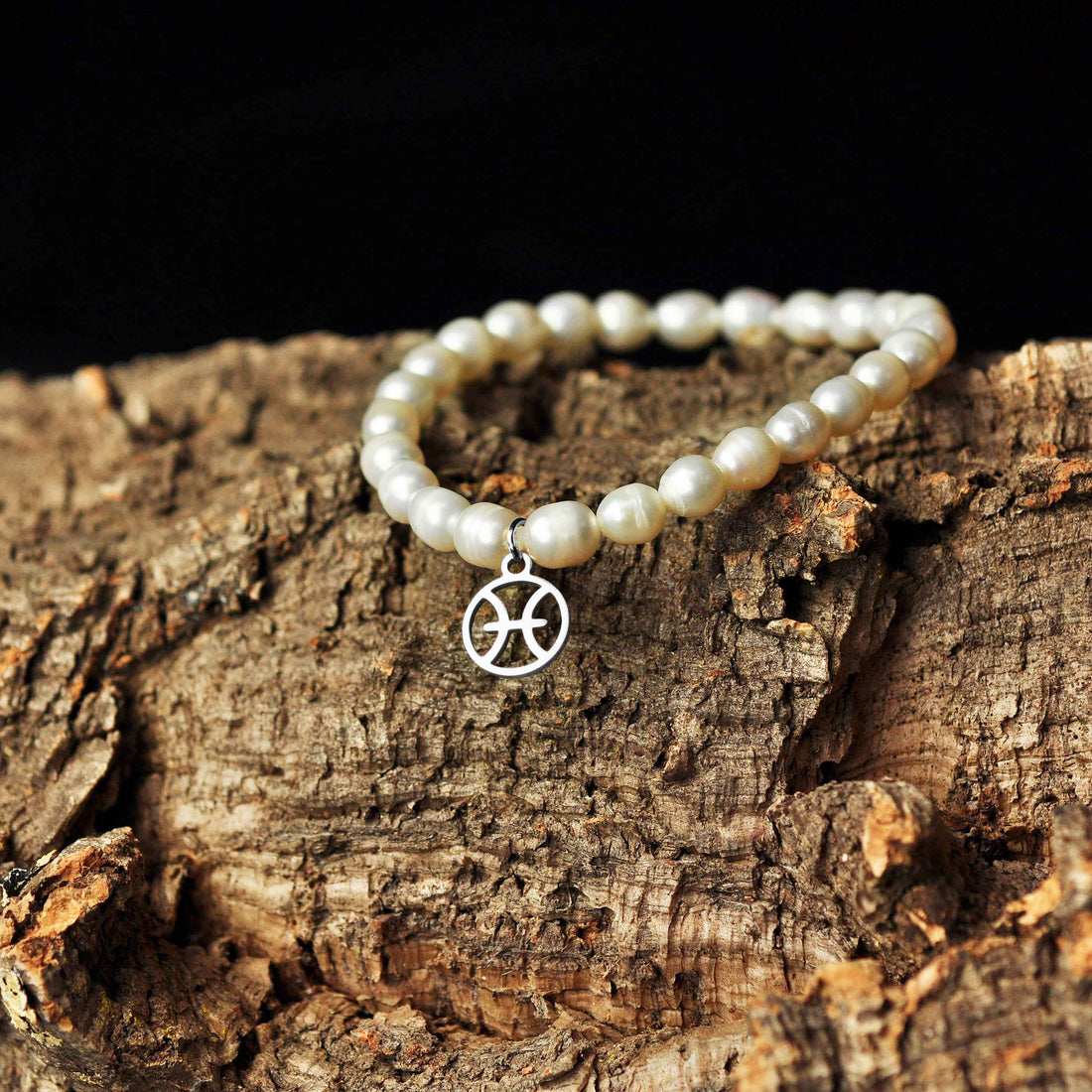 Wit zoetwater parel armband met zilver edelstalen symbool van sterrenbeeld Vissen liggend op schors | Parel armband Zilveren Sterrenbeeld Vissen