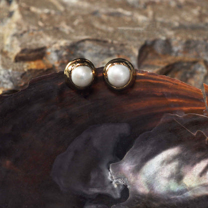 Witte zoetwater parel clips oorbellen met gouden rand, vooraanzicht hangend aan schelp | One Gold Clip Pearl