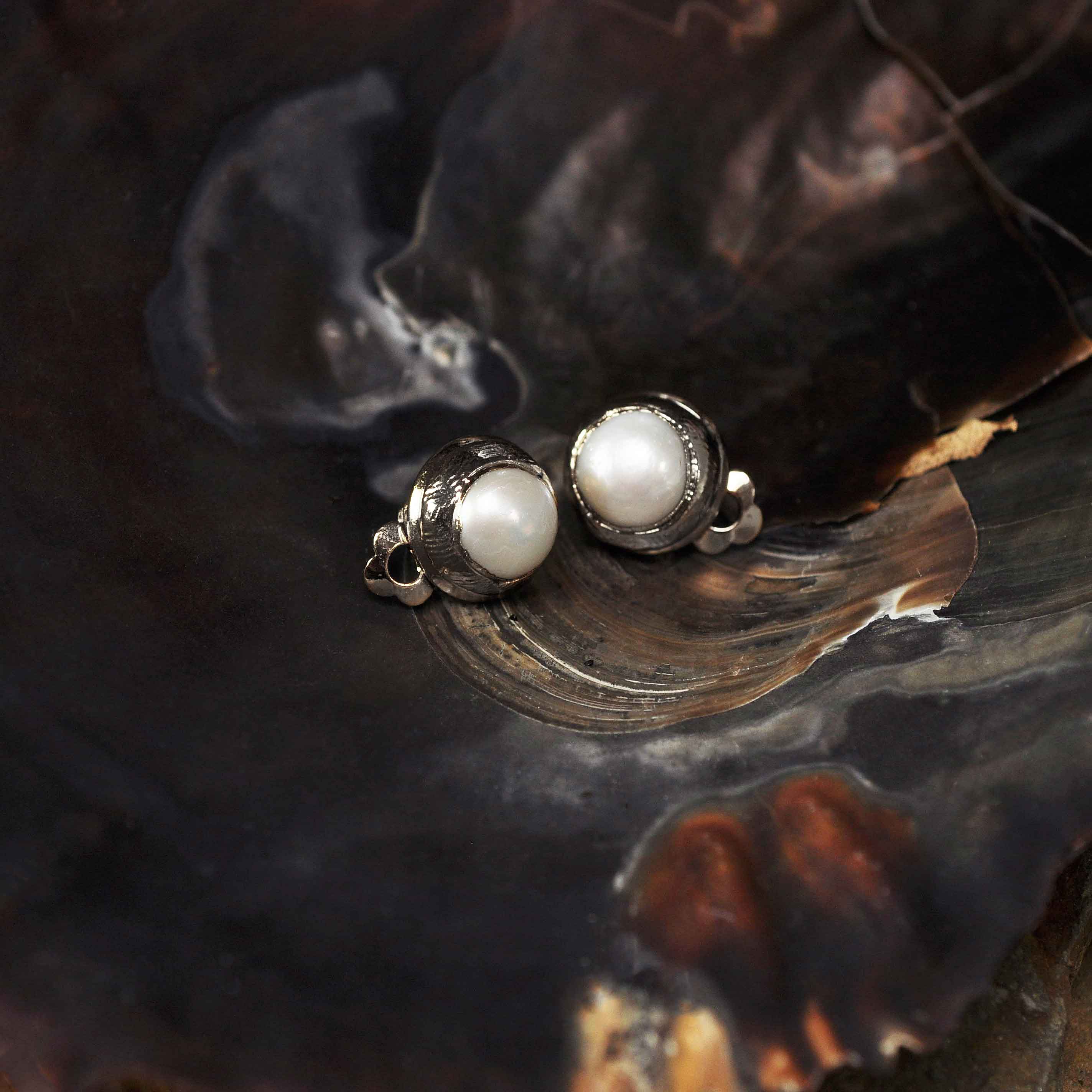 Witte zoetwater parel clips oorbellen met zilveren rand liggend in schelp | One Silver Clip Pearl