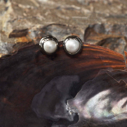 Witte zoetwater parel clips oorbellen met zilveren rand hangend aan schelp vooraanzicht | One Silver Clip Pearl