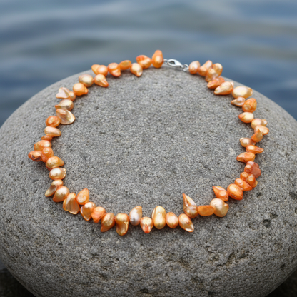 Zoetwater parelketting met oranje parels en sterling zilver (925) liggend op steen | Zaza