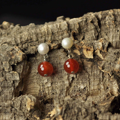 Zoetwater parel oorbellen met witte parel en rode agaat liggend op schors | Pearl Stud Red Agate