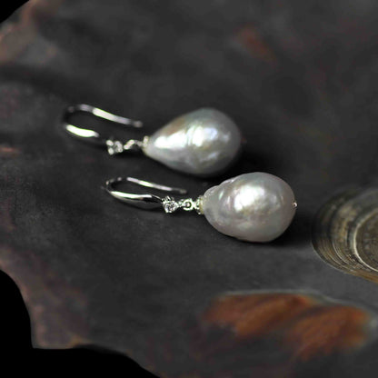 Grijze zoetwater parel oorbellen met sterling zilveren oorbelhaakjes en stras steentje liggend in schelp | Bling Kasumi Grey Pearl