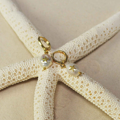 Witte zoetwater parel oorbellen met gouden zeester met oorringen liggend op het strand  | Gold Pearl Starfish