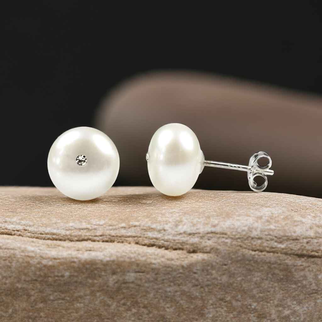 Witte zoetwater parel oorbellen met stras steentje liggend op beige steen voor en zijkant | Zoetwater parel oorbellen Bling Mea W