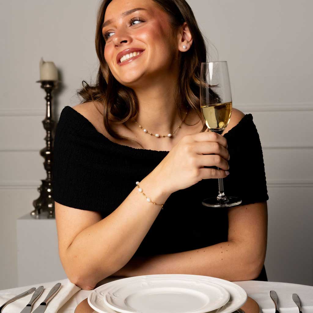 Witte zoetwater parelketting met goud edelstaal met model aan tafel | Parelketting Eline Goud