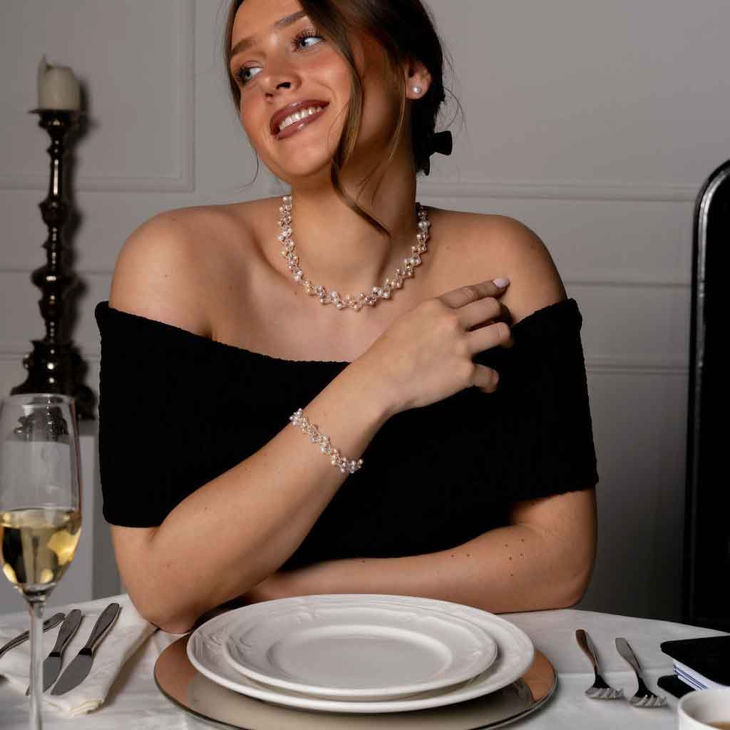 Zoetwater parel set bestaande uit een parelketting en parel armband met witte, zalm en roze parels en magneetslot op model aan tafel | set Felicia