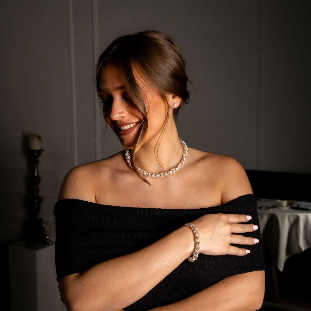 Witte zoetwater parel set bestaande uit een parelketting en parel armband met beige glaskristallen op model met zwarte jurk | set Pearl Crystal Clear