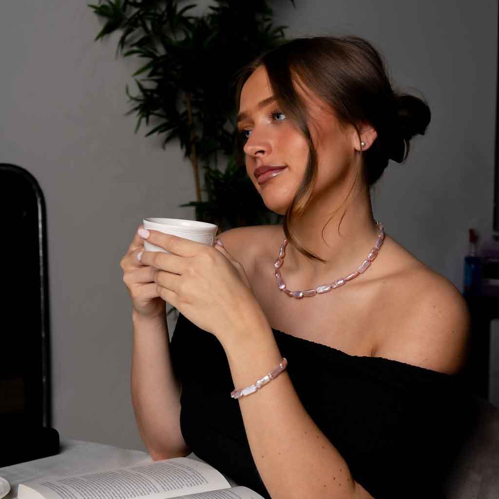 Handgeknoopte zoetwater parel set bestaande uit parelketting en parel armband met roze rechthoekige parels en sterling zilver (925) op model met boek | set Pearl Rectangle Pink