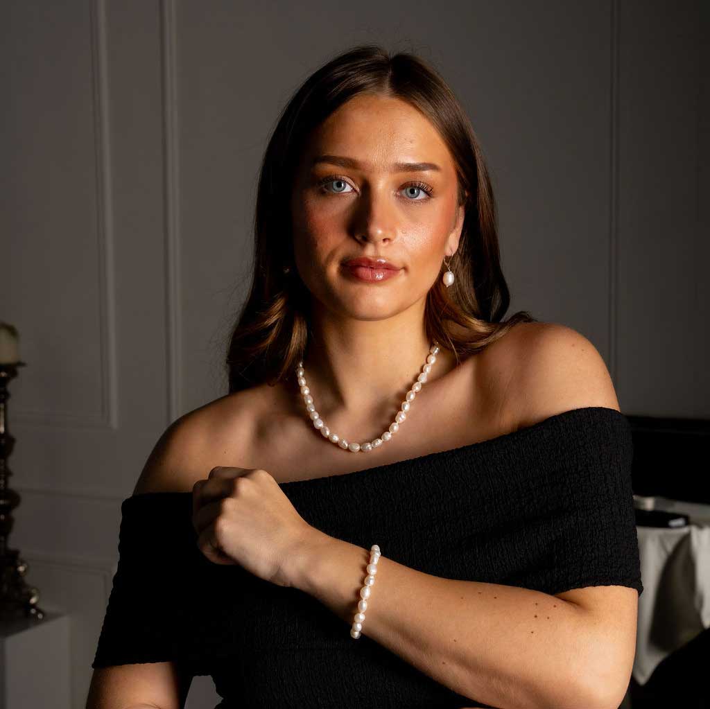Handgeknoopte zoetwater parelketting en armband met witte parels op model met zwarte jurk | Wola