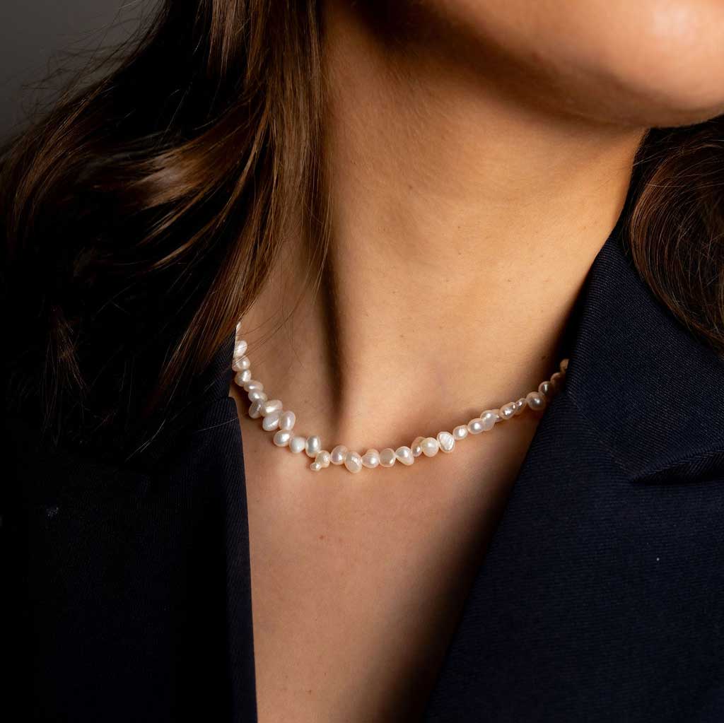 Zoetwater parelketting met kleine witte parels en goud edelstaal model met zwart jasje detail | Adalyn