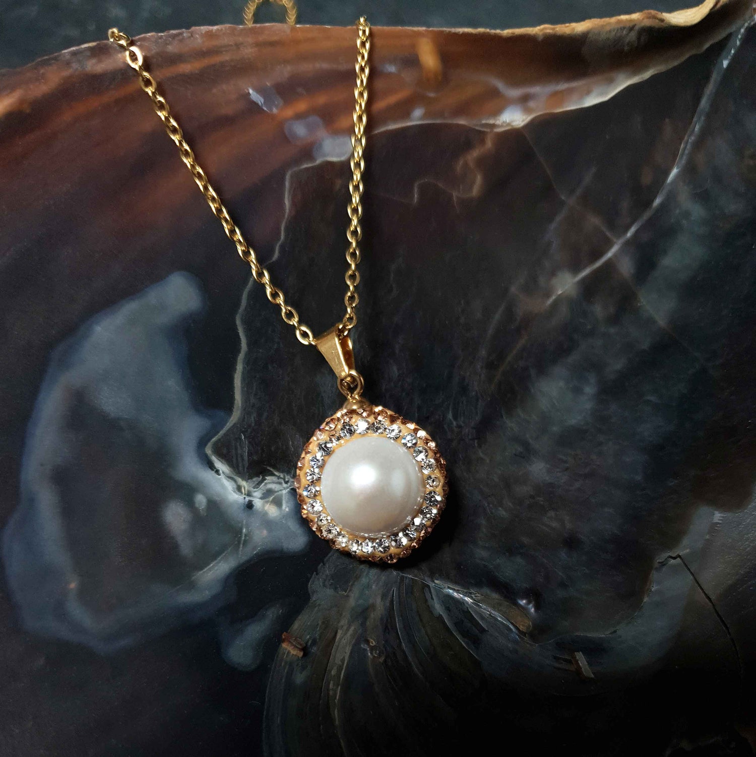 Detail van zoetwater parelketting met witte parel hanger, gouden stras steentjes en goud edelstaal liggend in schelp | Bright Golden Pearl