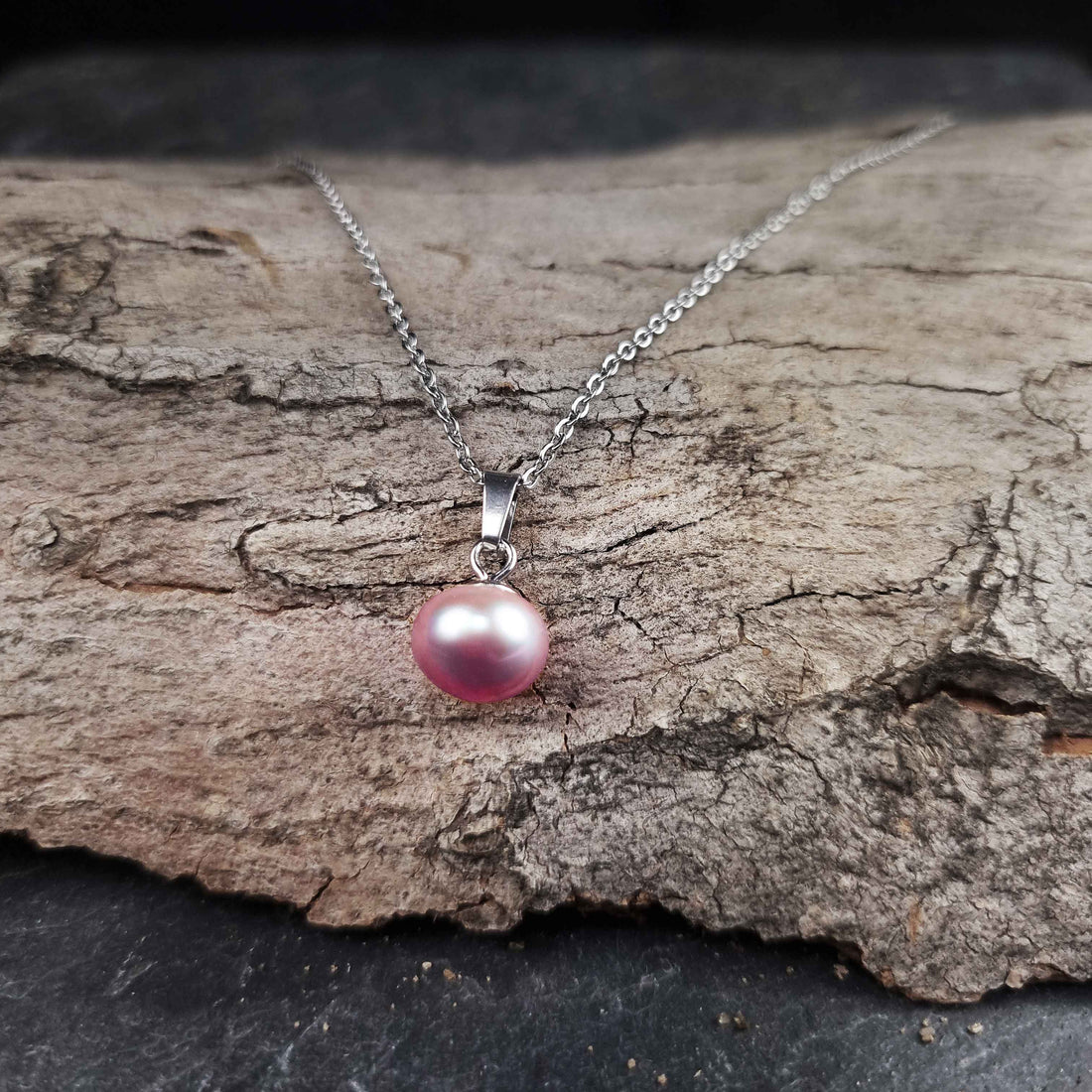 Zoetwater parelketting met roze parels en zilver edelstaal liggend op hout | set Brit P