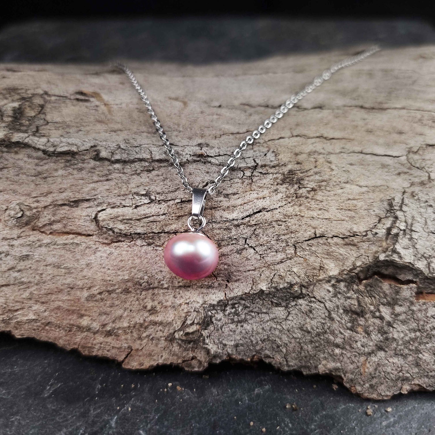 Zoetwater parelketting met roze parels en zilver edelstaal liggend op hout | set Brit P