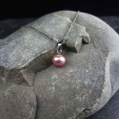 Zoetwater parelketting met roze parels en zilver edelstaal liggend op grijze steen | set Brit P