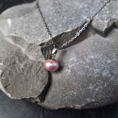 Zoetwater parelketting met roze parels en zilver edelstaal liggend op kei | set Brit P