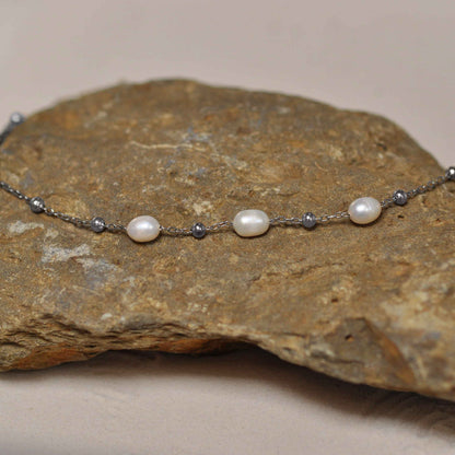 Witte zoetwater parelketting met zilver edelstaal liggend op steen | Parelketting Eline Zilver