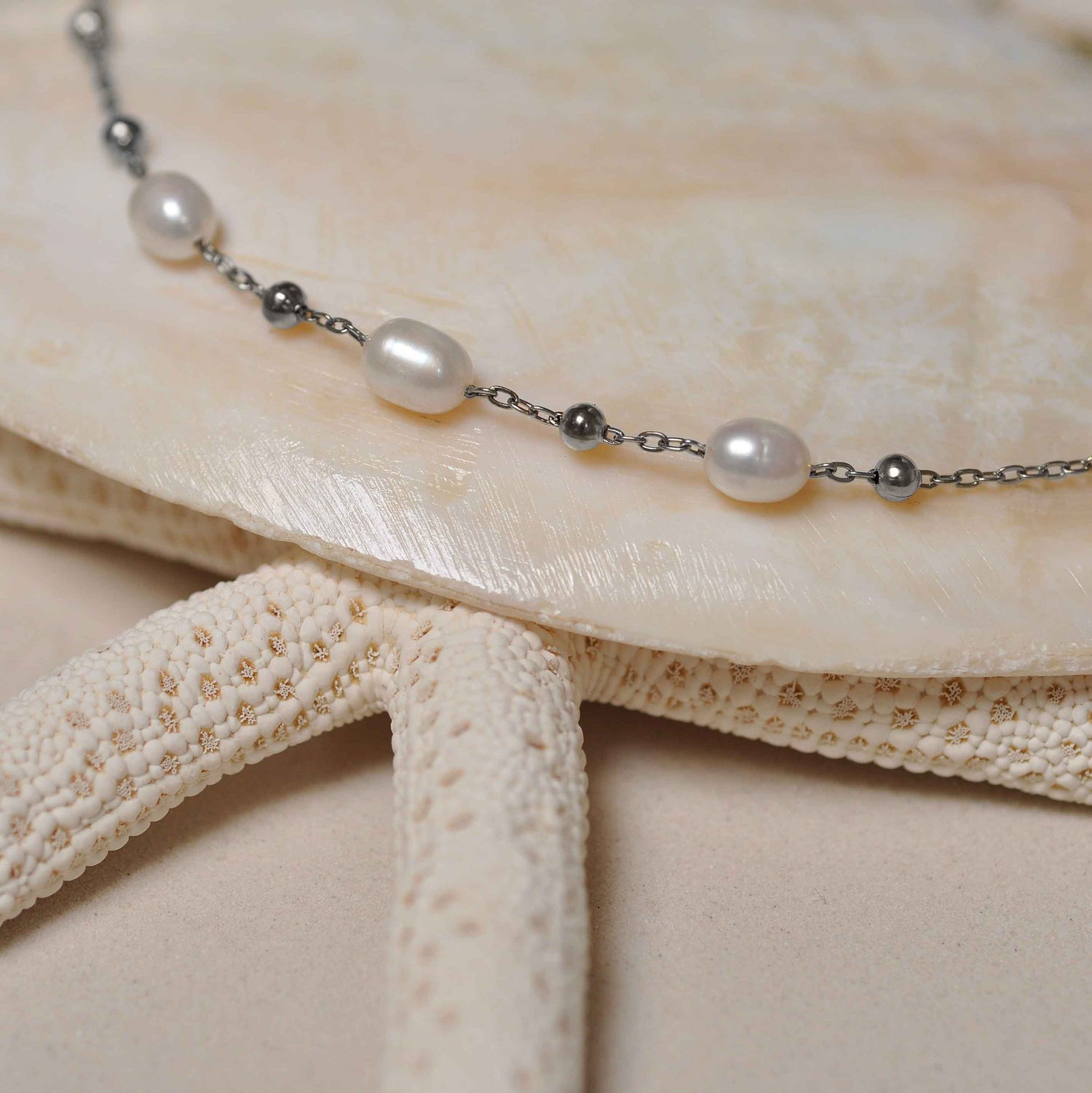 Witte zoetwater parelketting met zilver edelstaal liggend op witte schelp | Parelketting Eline Zilver