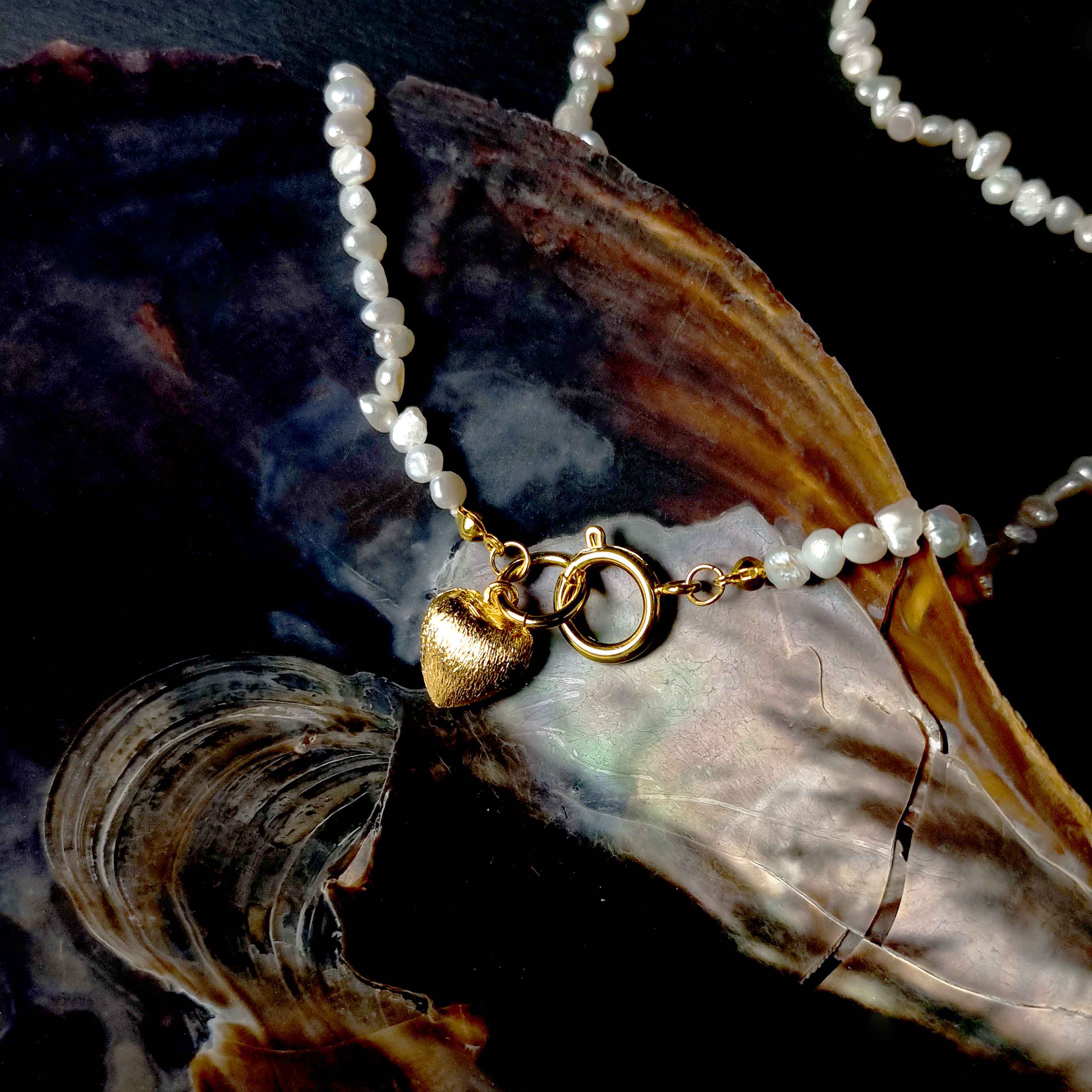 Witte zoetwater parelketting met gouden hart hangertje liggend in schelp