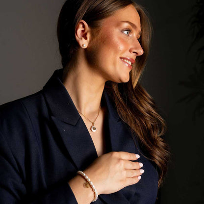 Zoetwater parelketting met witte parel hanger met gouden symbool van sterrenbeeld schorpioen en goud edelstaal op model met colbert jasje | Gouden Sterrenbeeld Schorpioen