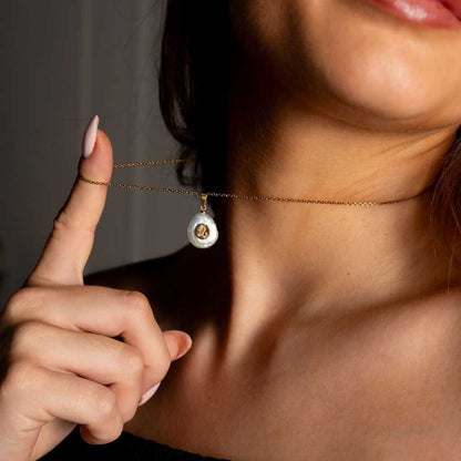 Detail van zoetwater parelketting met witte parel hanger met gouden symbool van sterrenbeeld steenbok en goud edelstaal om hals van model | Gouden Sterrenbeeld Steenbok