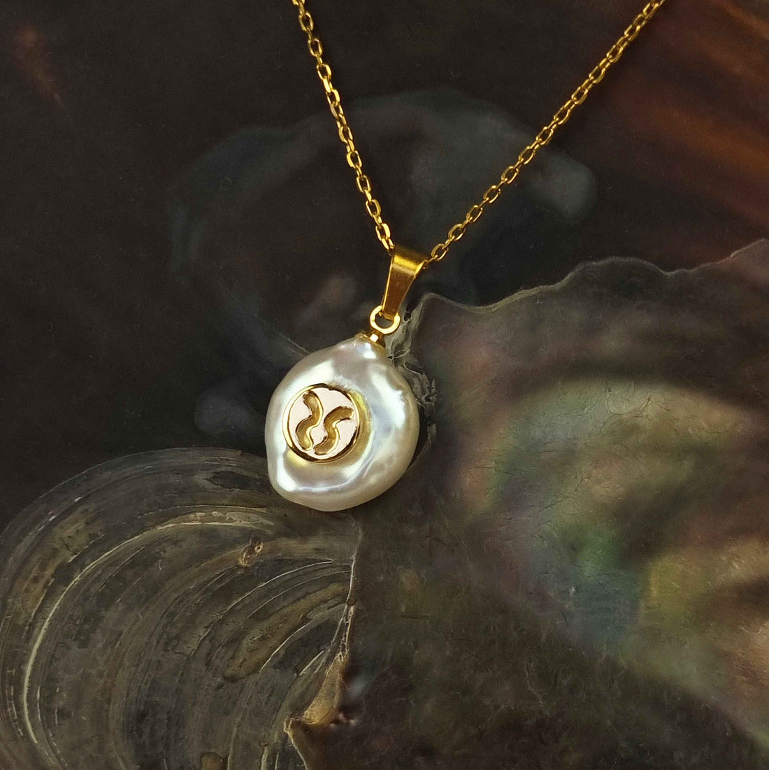 Detail van witte zoetwater parelketting met goud edelstaal en sterrenbeeld STIER liggend in schelp | Gouden sterrenbeeld STIER