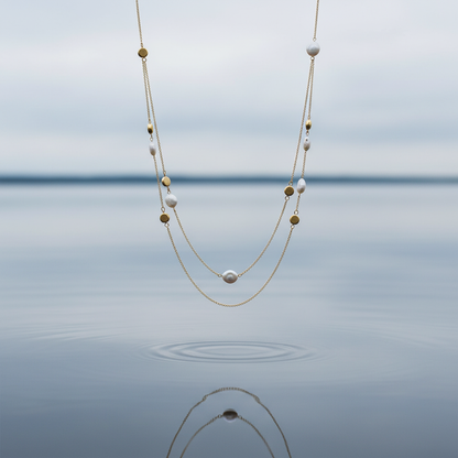 Lange witte parelketting met goud verguld zilver hangend boven water - Marceline