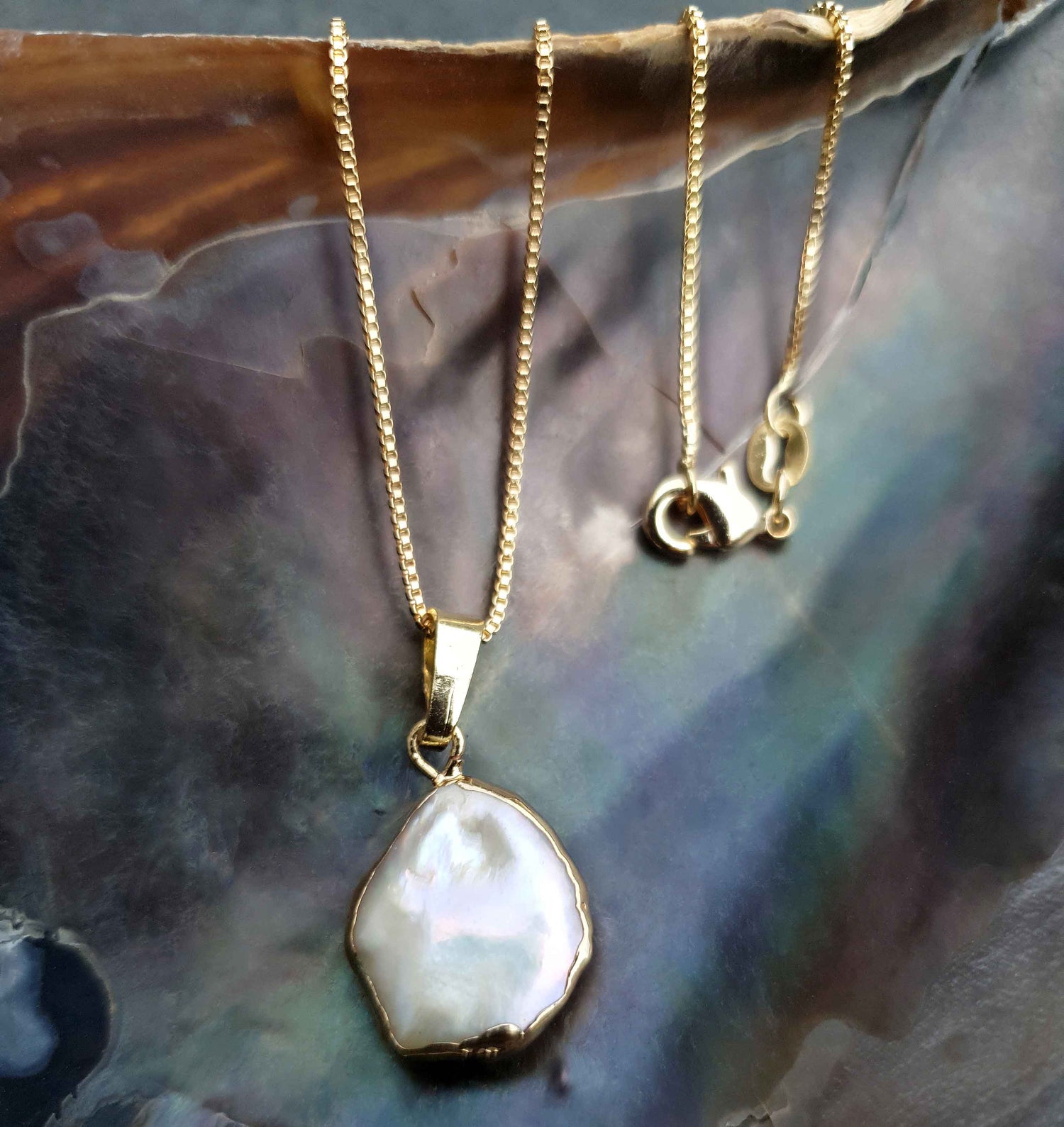 Detail van zoetwater parelketting met witte parel hanger hangend aan schelp | One Gold Coin Pearl Chain