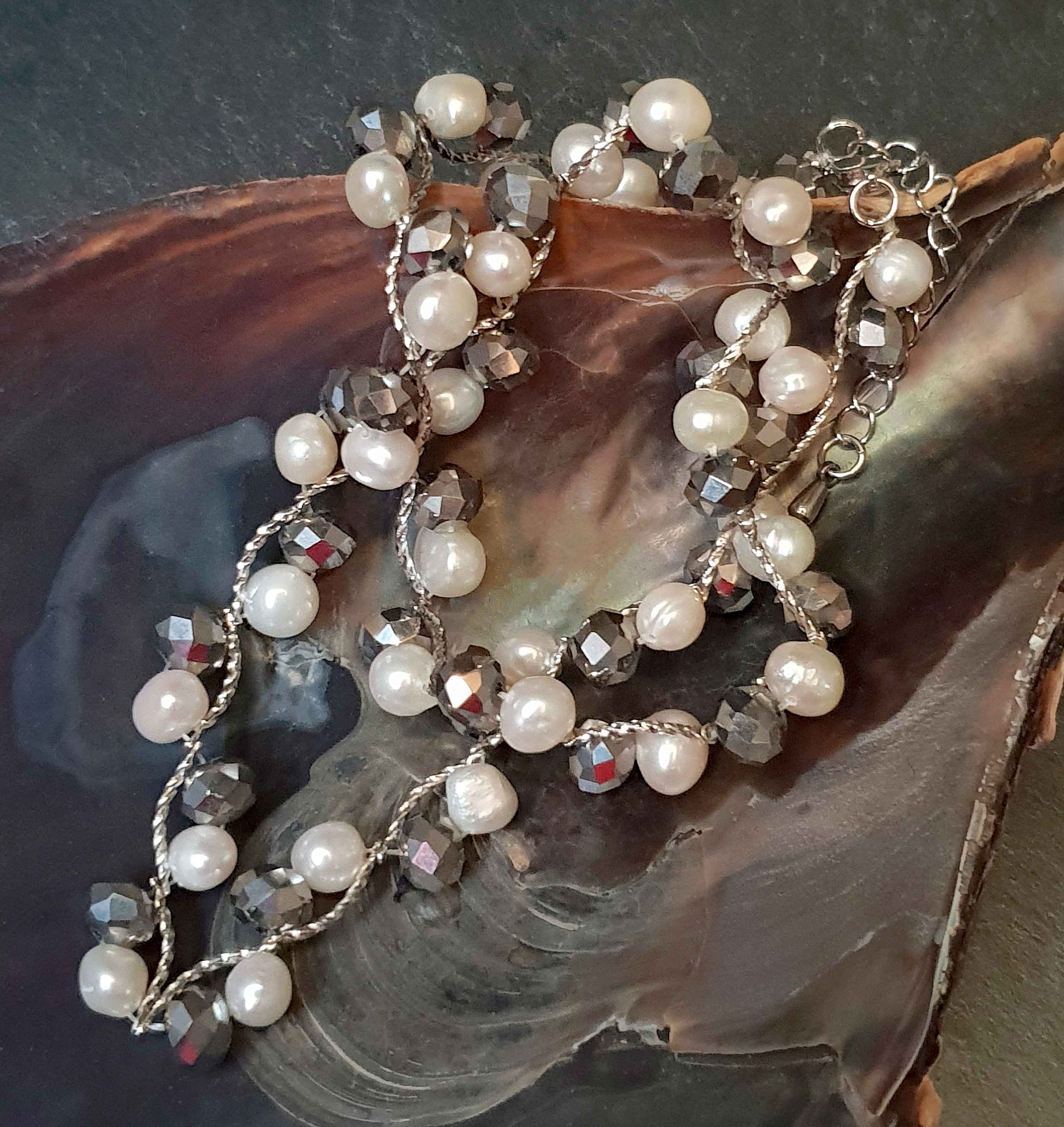 Witte zoetwater parelketting met zilver facet geslepen glas kristallen liggend in schelp | Silana