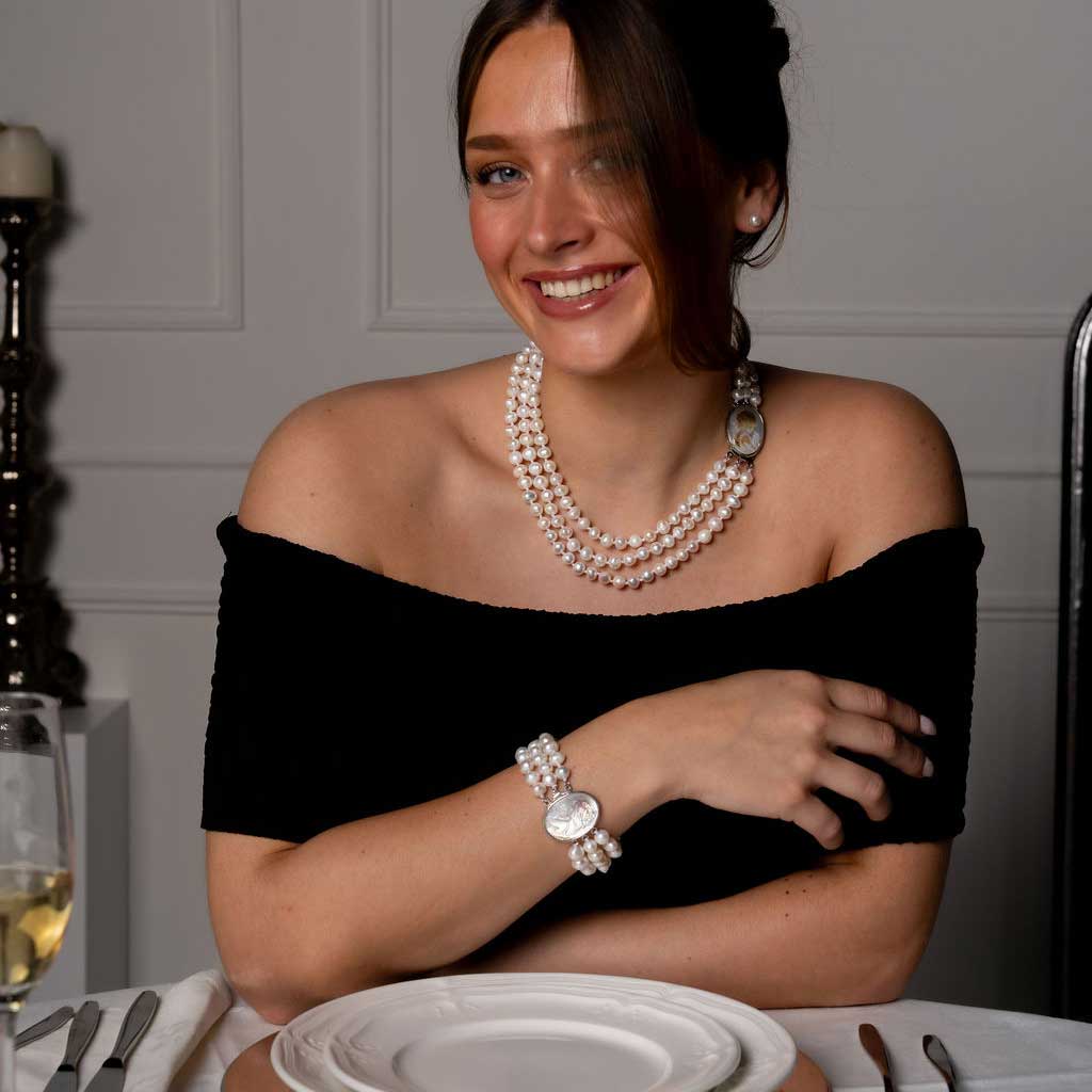 Handgeknoopte zoetwater parelketting met witte parels in 3 rijen en parelmoeren slotje op model aan tafel | Victoria